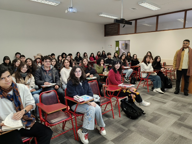 Estudiantes PAT en sala de clases, sonríen para fotografía. En esquina derecha profesor está de pie sonriendo a cámara. 